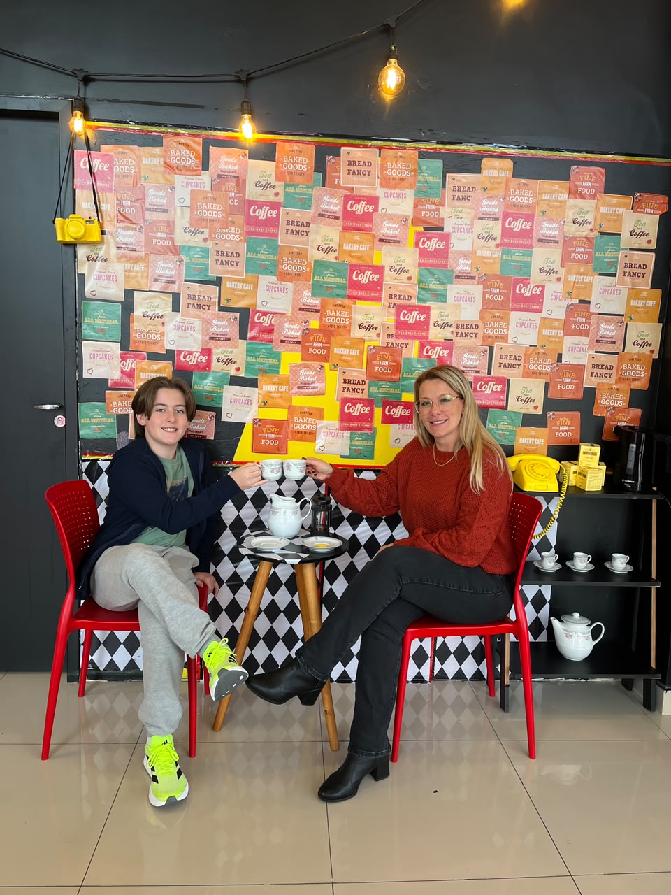 Aluno e professora brindando com xícaras de chá durante o English Tea na Tell Me