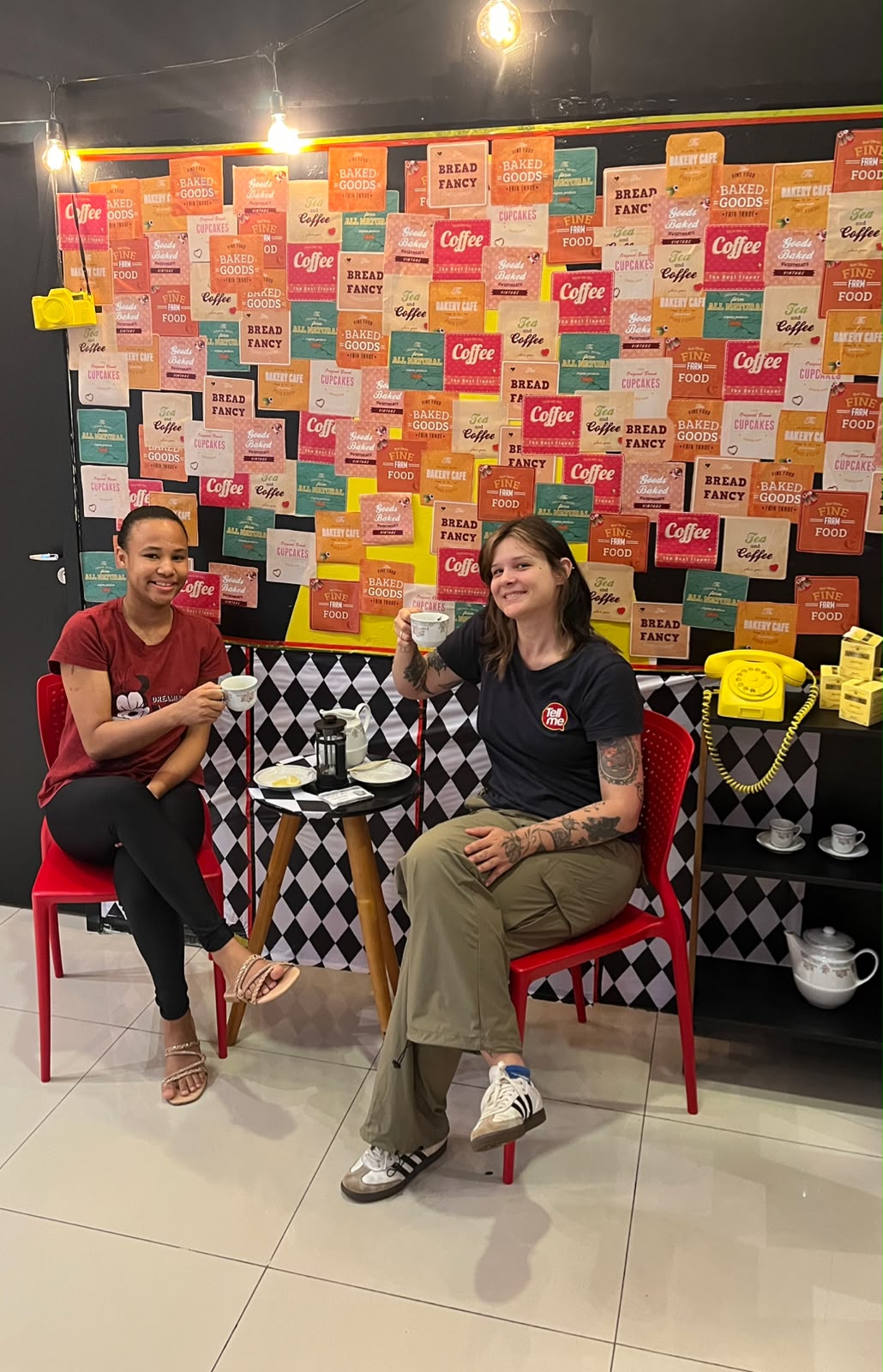 Duas alunas brindando com xícaras de chá durante o English Tea na Tell Me