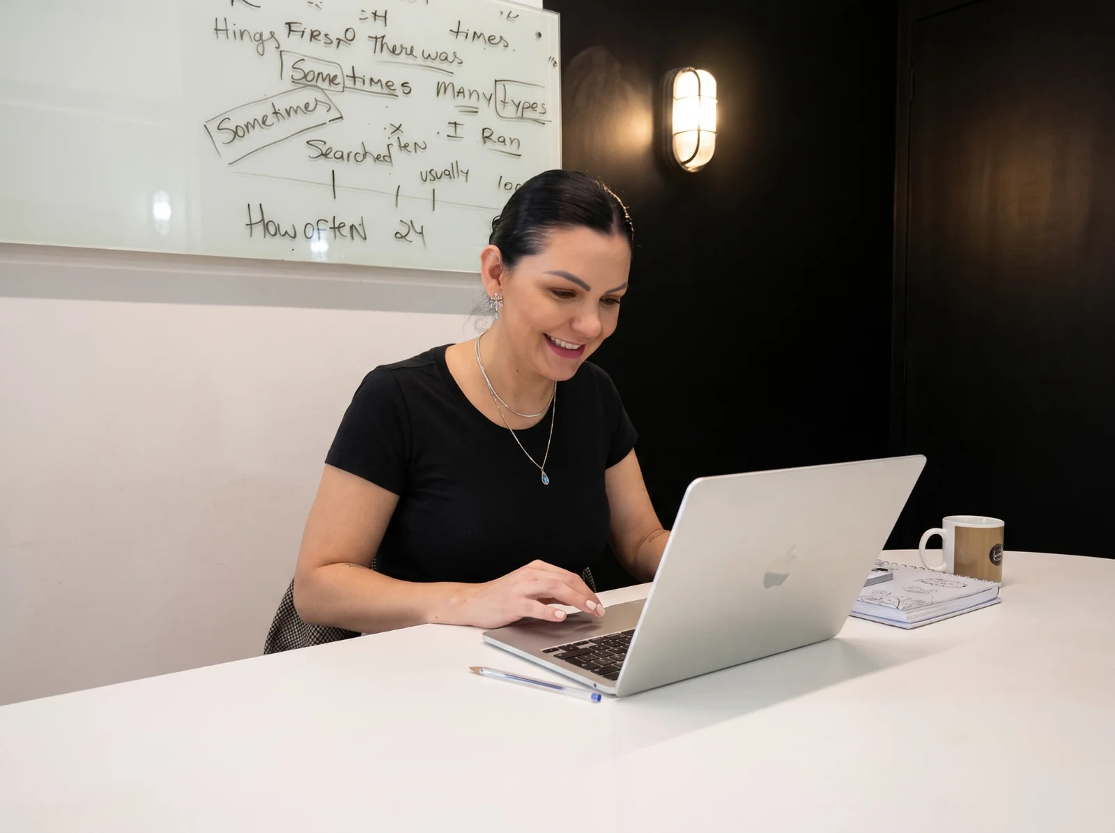 Professora da Tell Me conduzindo uma aula de inglês online ao vivo pelo laptop, com quadro branco ao fundo